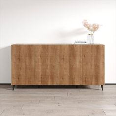 a wooden cabinet sitting on top of a hard wood floor next to a white wall