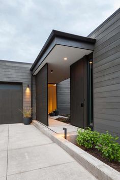 the entrance to a modern home with concrete steps and plants in pots on either side