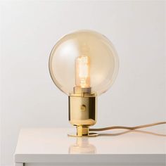 a light bulb sitting on top of a white table next to a lamp plugged in