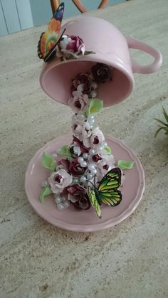 two pink plates with flowers and butterflies on them sitting on a counter top next to a potted plant