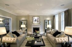 a living room filled with furniture and a fire place in front of a mirror on the wall