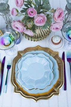 there is a table setting with pink roses and gold trimmings on the plate