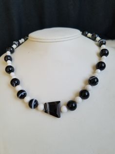 "This vintage Black Banded Sardonyx beaded necklace is strung onto a white cord and closed of with a silver tone lobster clasp. The stones are in a round medium size with the exception of the middle stone that is shaped in an odd triangle. The small round white stones are Moonglow Stones. The pattern is White alternates with the Black sandwiched between the Whites stones. The necklace is sturdy and in excellent vintage condition. The necklace will arrive in a gift box with FREE SHIPPING. Measure White Hand-strung Round Necklaces, Onyx Large Beads Jewelry For Gifts, Vintage White Gemstone Beads Jewelry, Vintage White Jewelry With Gemstone Beads, Onyx Jewelry With Large Beads As Gift, Vintage White Hand-strung Necklaces, Vintage White Hand-strung Jewelry, Adjustable Onyx Round Bead Necklaces, Adjustable Onyx Bead Necklaces