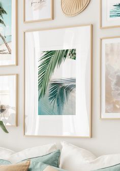 a bed with pillows and pictures on the wall above it, including palm tree leaves