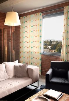 a living room with two couches and a table in front of a brick wall