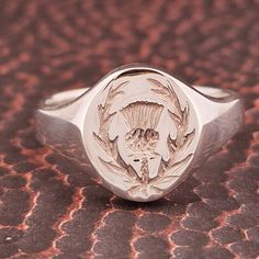 Elevate your style with our expertly handcrafted Scottish Thistle Silver Signet Ring for Men. This heavyweight masterpiece, made from 925 sterling silver and weighing 7.9 grams, exudes a remarkable feel. The large 14mm by 12mm oval plate, adorned with a hand-engraved Scottish thistle, pays homage to heritage--ideal for rugby enthusiasts and proud Scots. Hallmarks from Birmingham, UK, guarantee its quality. Whether a retirement gift, a Peaky Blinders-inspired accessory, or a symbol of Scottish pride and rugby love, this ring fits the bill. Inquire for additional sizes, and enjoy eco-conscious packaging in our FSC-certified branded box. Scottish Jewellery, Scottish Thistle, Oval Plates, Silver Signet Ring, Peaky Blinders, Ring Fit, Retirement Gifts, Hand Engraving, Signet Ring