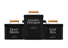 the laundry detergent canisters are black with white lettering on them and bamboo handles