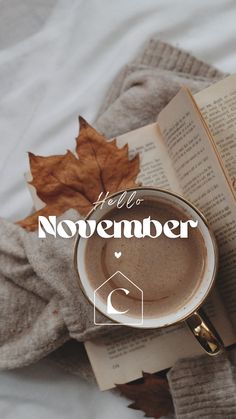 a cup of coffee sitting next to an open book on top of a blanket with the words hello november