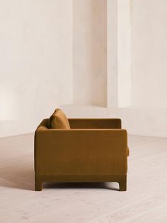 a couch sitting on top of a hard wood floor next to a white wall in an empty room