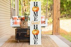 a wooden sign that says home sweet home with pumpkins on it sitting in front of a porch