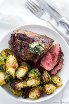 a white plate topped with steak and brussel sprouts