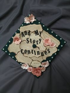 a graduation cap that says and my story continues with flowers on the front, and an old book page in the middle