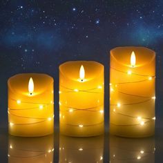 three lit candles sitting next to each other in front of a night sky with stars