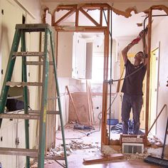 a man standing in the middle of a room with tools on his head and ladders