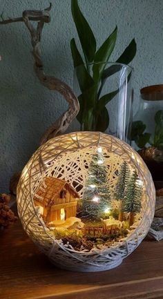 a christmas scene in a basket on a table with trees and lights around the base