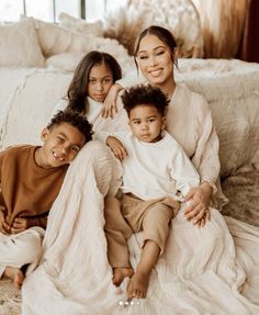 a woman and two children are sitting on a bed with their arms around each other