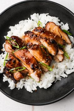 chicken and rice on a black plate with chopsticks