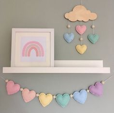 there are hearts hanging on the shelf with a rainbow in the background and a cloud above it