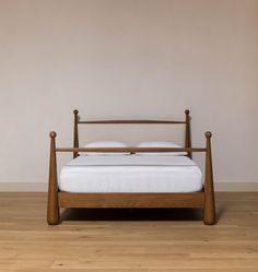 a bed sitting on top of a hard wood floor next to a white wall in a bedroom