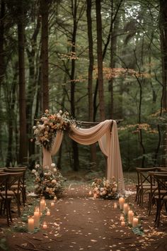 an outdoor wedding setup with candles and flowers on the ground, surrounded by trees in the background