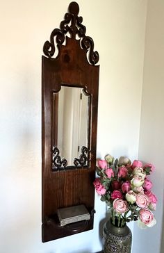 a vase with flowers sitting next to a mirror