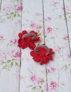 two red crocheted shoes sitting on top of a white table next to pink flowers