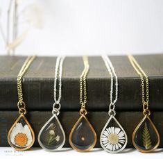 "Our Large Teardrop frame is a stunning classic and available in a variety of real preserved botanicals. Choose from a 24k gold or .999 sterling silver plated finish.  Baby's Breath is a symbol of purity of heart Daisy is a symbol of hope The Mustard Seed is a symbol of faith The Fern is a symbol of sincerity Pendant hangs from a gold or silver plated chain, plain or satellite, and available in 26\" or 30\" lengths. Model is wearing a 26\" chain. Materials are tarnish resistant. However, please Nature-inspired Hypoallergenic Teardrop Jewelry, Nature-inspired Gold Teardrop Jewelry, Dainty Teardrop Nickel-free Necklace, Handmade Gold Teardrop Drop Necklace, Teardrop Necklace With Natural Inclusions, Gold Sterling Silver Necklaces With Pressed Flowers, Elegant Teardrop Birth Flower Jewelry, Gold Sterling Silver Necklace With Pressed Flowers, Teardrop Pendant Jewelry With Flower Charm As A Gift