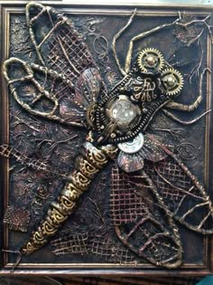 an intricately decorated metal box with a dragonfly on it's back side