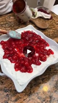 a bowl filled with cherries sitting on top of a counter next to a spoon