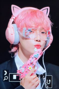 a person with pink hair wearing headphones and holding a cat shaped object in front of their face