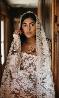 a woman wearing a veil and holding a cup in her hand while standing next to a door