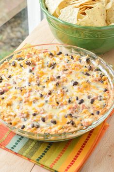 a casserole dish with tortilla chips in it and a bowl of salsa