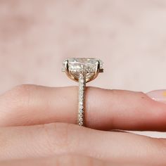 a woman's hand holding an engagement ring with a diamond on the top and side