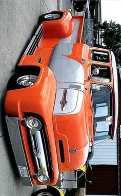 an orange sports car parked on the side of a building