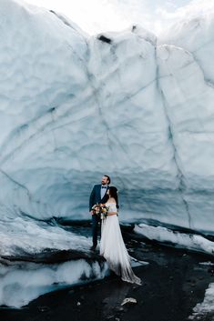 a bride and groom standing in front of an ice cave