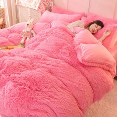 a girl is sleeping in her bed with pink comforter and teddy bear pillows on it