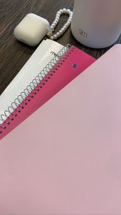 a pink spiral notebook next to a coffee mug