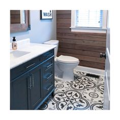 a white toilet sitting next to a sink in a bathroom under a window on top of a wooden wall