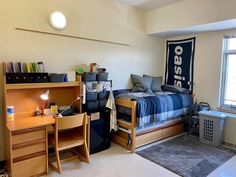 a dorm room with a bed, desk and chair