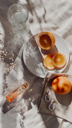 an orange cut in half on a plate next to some other fruit and glassware