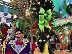 a man standing in front of a christmas tree with decorations on it's head