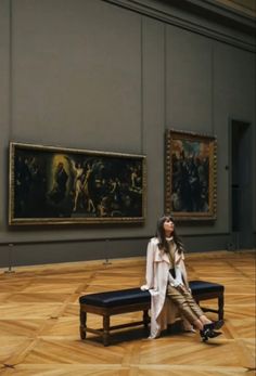 a woman sitting on a bench in an art gallery