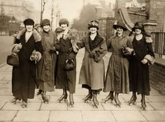 an old black and white photo of women in long dresses standing on the side walk