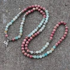 Amazonite Is A Soothing Stone. Wear It And You Will Immediately Feel A Sense Of Inner Peace And Balance. It Possesses A Powerful Energy, Like The River Of Which It Bears The Name, But It Is Nevertheless Capable Of Taming And Calming Negativity And Anger. Rhodonite Helps To Balance The Emotions And Calm Impatience. Rhodonite Is A Very Supportive Stone That Works With The Heart Chakra To Attract Love And Ground Negative Energies. Physically, Rhodonite Is Believed To Support Detoxification And Heal Multicolor Rose Quartz Round Bead Jewelry, Spiritual Pink Beaded Crystal Necklaces, Bohemian Pink Crystal Necklace With Gemstone Beads, Pink Bohemian Crystal Necklace With Gemstone Beads, Adjustable Pink Beaded Necklace With 108 Beads, Adjustable Hand-strung Pink Necklace, Beaded Rose Quartz Crystal Necklace, Pink Rose Quartz Gemstone Beaded Necklace, Pink Rose Quartz Gemstone Beaded Necklaces