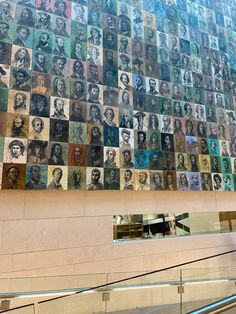 an escalator in front of a wall with many pictures on it