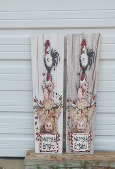 two wooden signs with farm animals painted on them sitting next to each other in front of a garage door