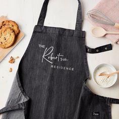 an apron that says the kitchen residence next to cookies