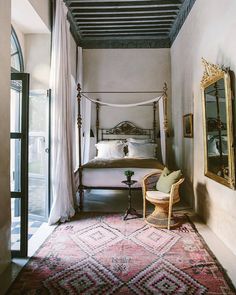 a bedroom with a canopy bed, chair and rug on the floor in front of it