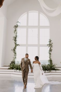 a bride and groom holding hands in front of a large window