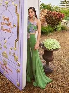 Make a statement with our moss green one-shoulder top, lavishly adorned with hand-embroidered 3D flowers, beads, and crystals. Paired with a matching georgette gharara, this ensemble offers a perfect blend of glamour and sophistication for any occasion. Glamorous Green Choli For Festive Season, Glamorous Green Choli For Wedding, Glamorous Green Choli For Festive Occasions, Festive Green Glamorous Choli, Glamorous Festive Green Choli, Glamorous Fitted Green Choli, Glamorous Green Lehenga For Wedding, Glamorous Green Sets For Reception, Glamorous Festive Green Sets